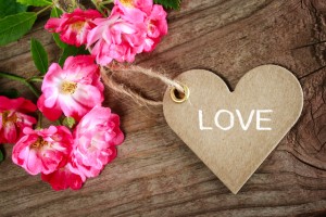 Love message on heart shaped card with roses on wood background