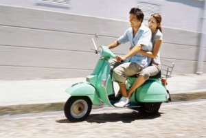 Young couple riding on a scooter and smiling